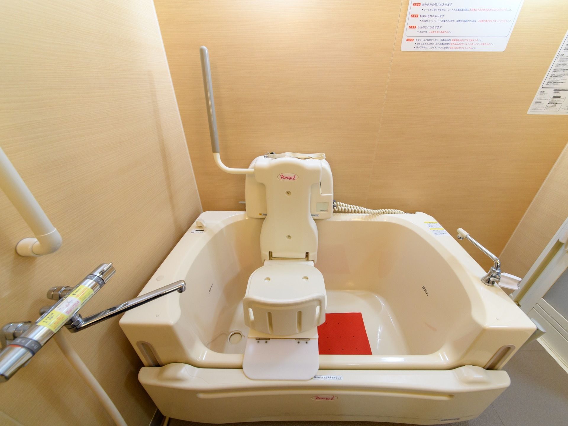 機械浴槽が設置されている。椅子に座りながら入浴ができる。壁には手すりが付いているため、安全な造りである。