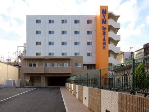 広い敷地内に立っている、外階段がある六階建ての建物