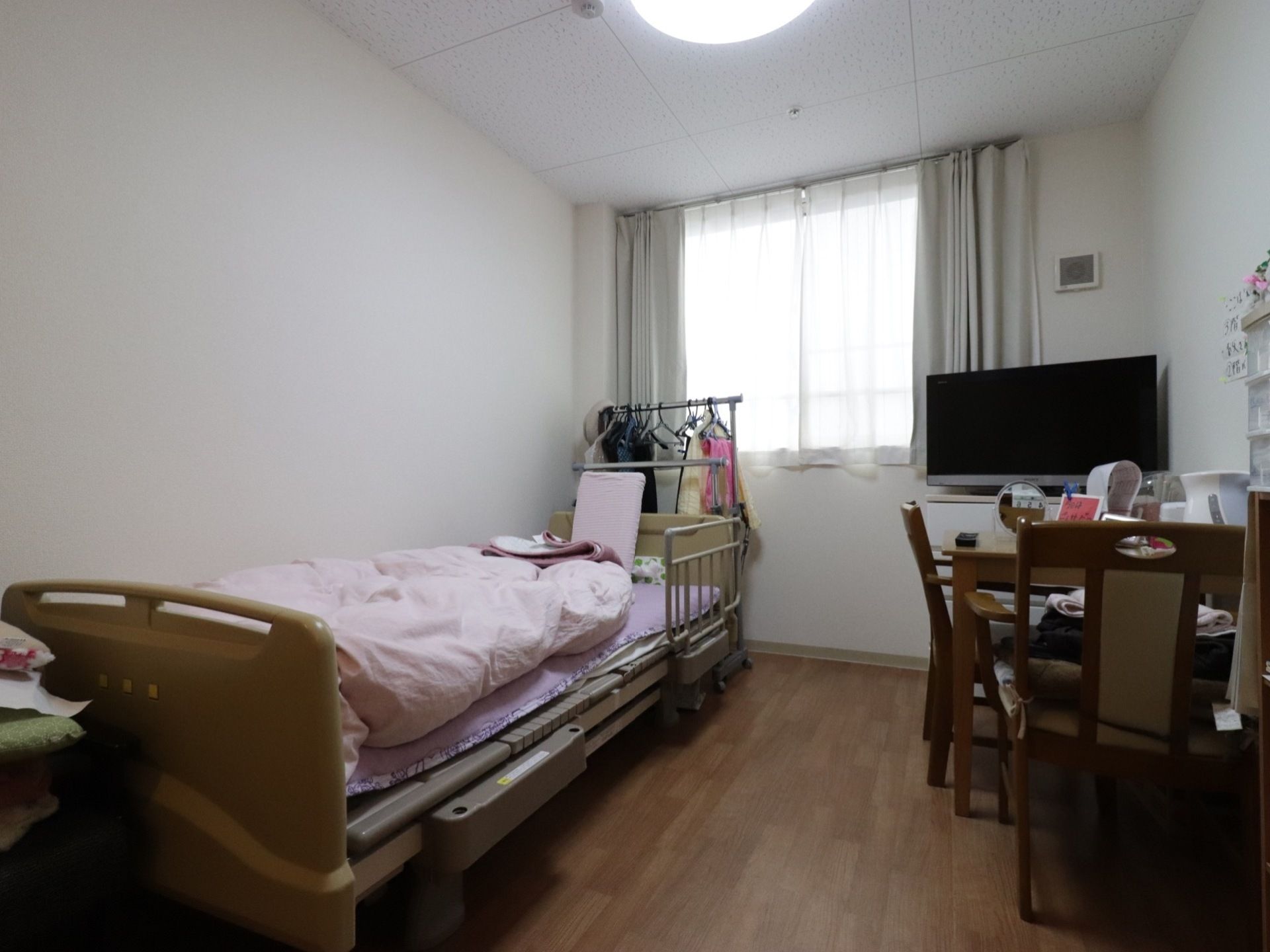 居室には柵付きのベッドが置かれている。ベッドの近くにはハンガーラックがあり、服などがかけられている。