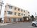 施設は三階建てである。入口には花壇が並べられていて、大きな屋根が取付けられている。敷地内には車が1台止められている。