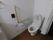 温水洗浄便座のトイレを設置している。壁には呼び出しボタンがあり、いざという時に安心である。白い壁の清潔感のあるスペースである。