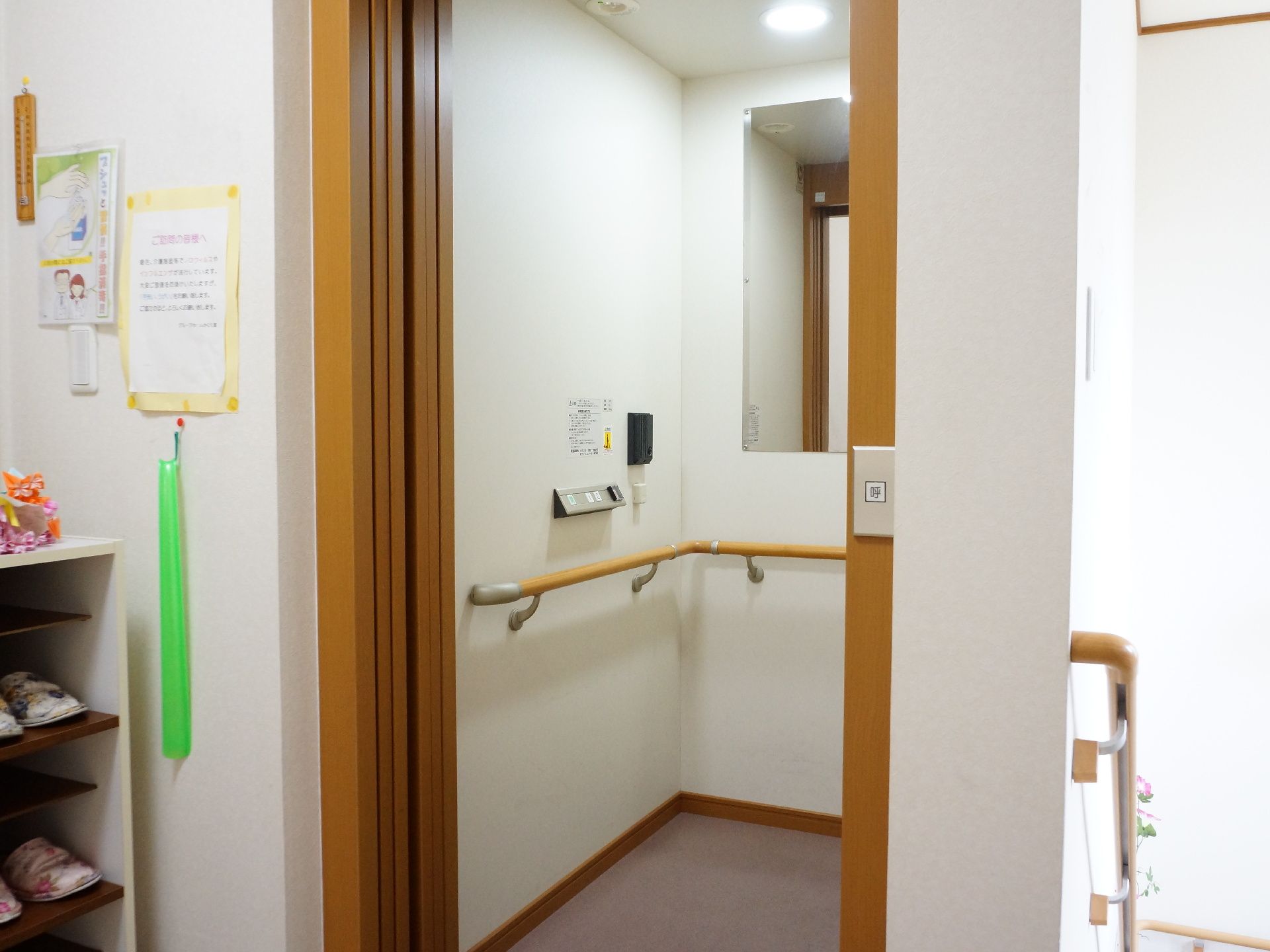 エレベーター内は明るく、鏡がある。壁全面に手すりが設置されているので、安心して利用できる。エレベーターの隣には、スリッパが置かれた棚がある。