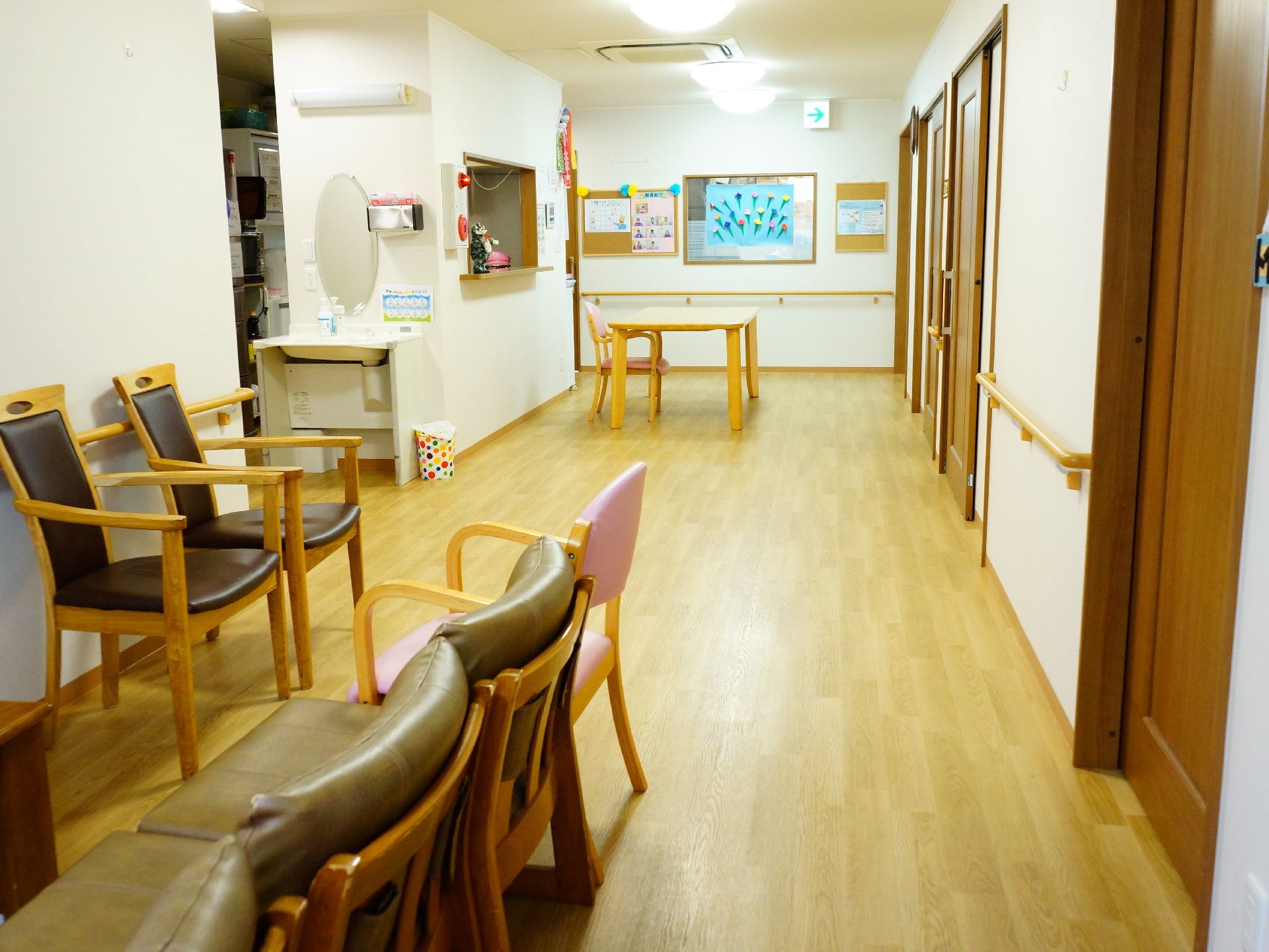 長く伸びた廊下の壁には手すりが設置してある。椅子が何脚も置かれており突き当たりの壁にはいくつもの掲示物が張り出されている。