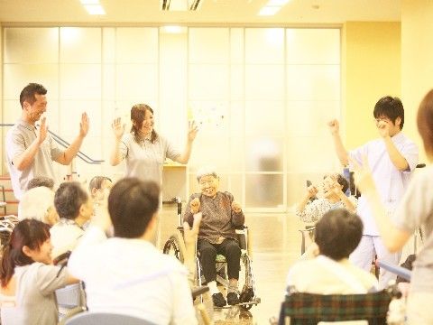 スタッフと一緒に、笑顔で手遊びを楽しんでいる入居者たち