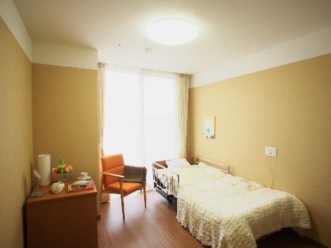 居室はお好みの家具を自由に持ち込んでいただけるように、ゆったりとしたスペースを設けている。ベッドの横の壁にナースコールを備えている。