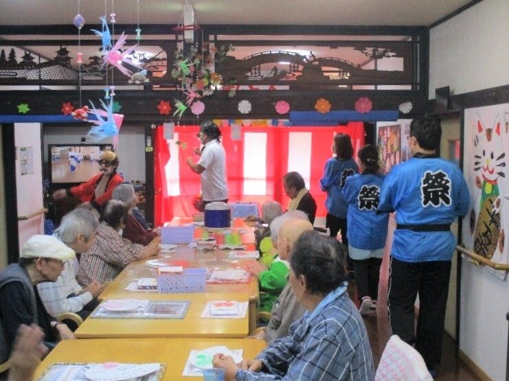 青い法被を着たスタッフが夏祭りを盛り上げる様子