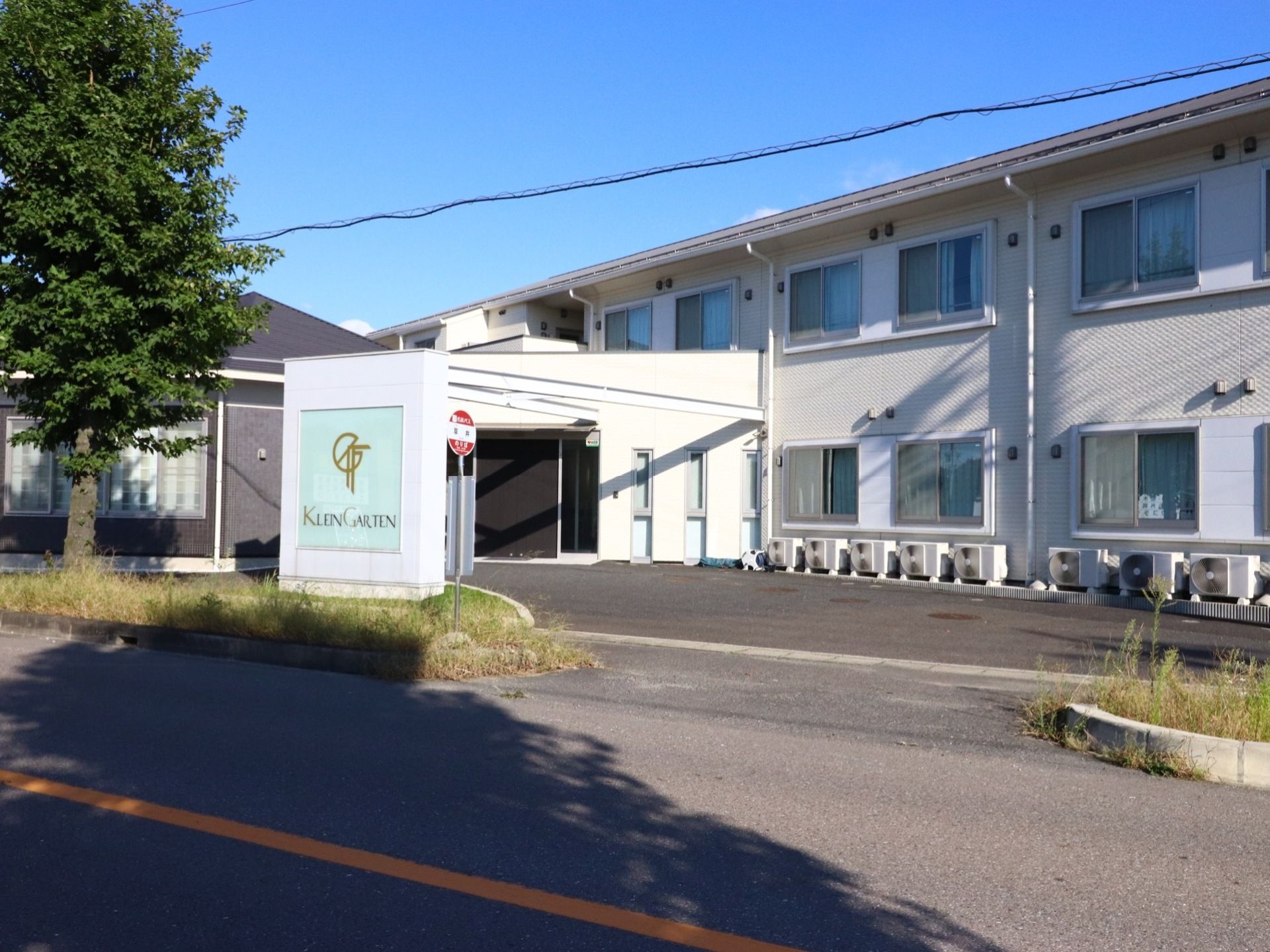 施設は２階建ての白い建物の住宅棟で、入口の近くにはアスファルトを敷いたロータリーがあり、バス停がある。