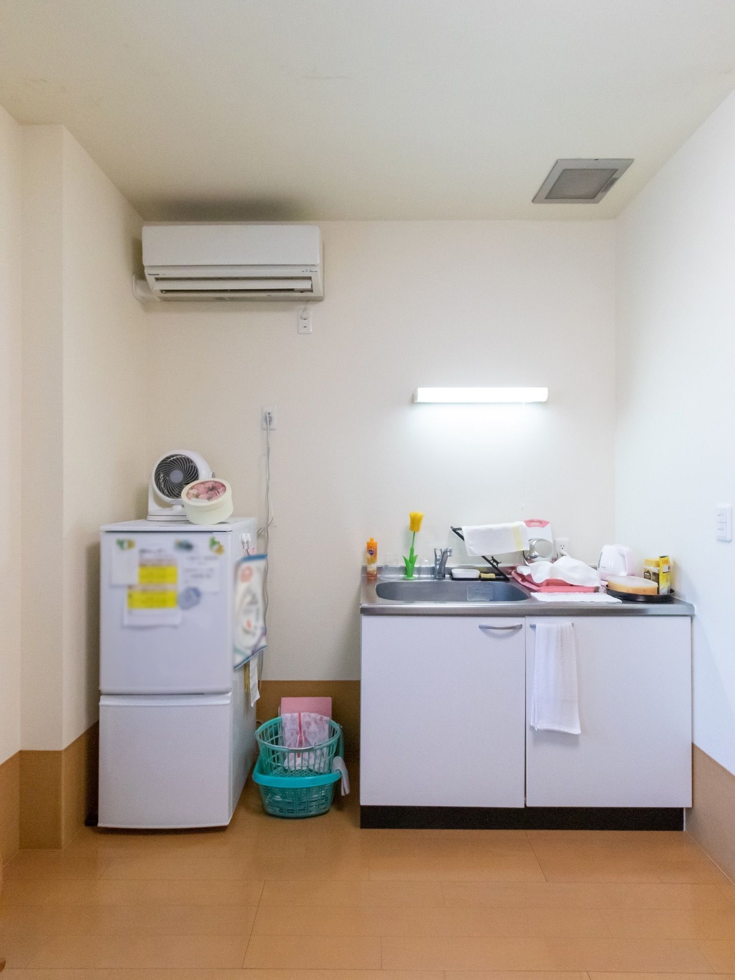 エアコンが完備されている居室である。キッチンの横には冷蔵庫が設置されており、上には扇風機が置かれている。