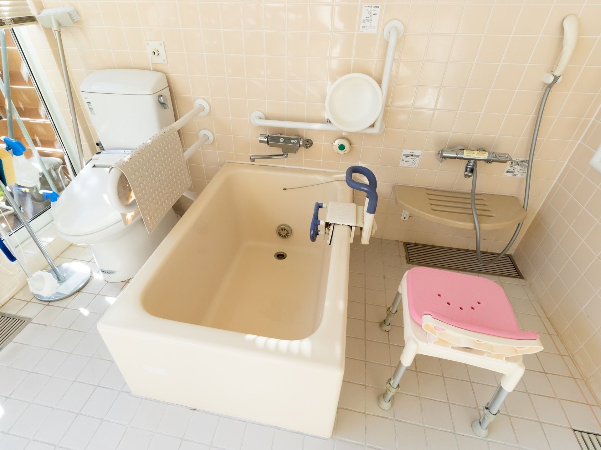トイレが備え付けられている浴室で、浴槽には可動式の手すりが取り付けられている。洗い場には、椅子が用意されている。