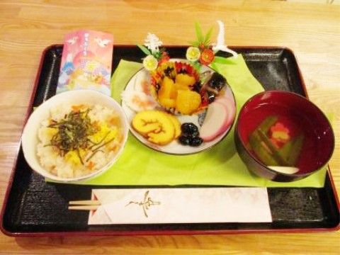 ご飯とお吸い物、お節が飾りと共に皿に盛りつけられているお膳