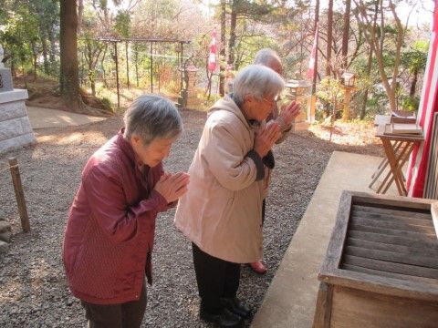 神社の賽銭箱の前で手を合わせている、三人の入居者様