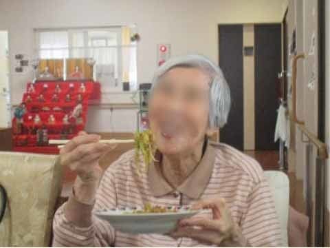 「グループホームひかり新横浜新羽」入居者様がお食事を食べている様子。満面の笑顔でお食事を楽しんでおられます。笑顔から察するに、きっと美味しいのでしょう。