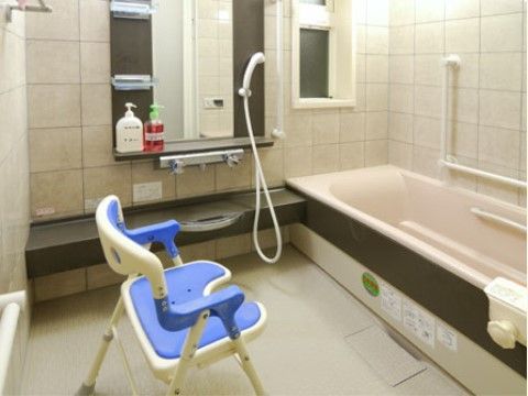鏡が大きく小窓が付いている、水色の椅子が置かれた浴室