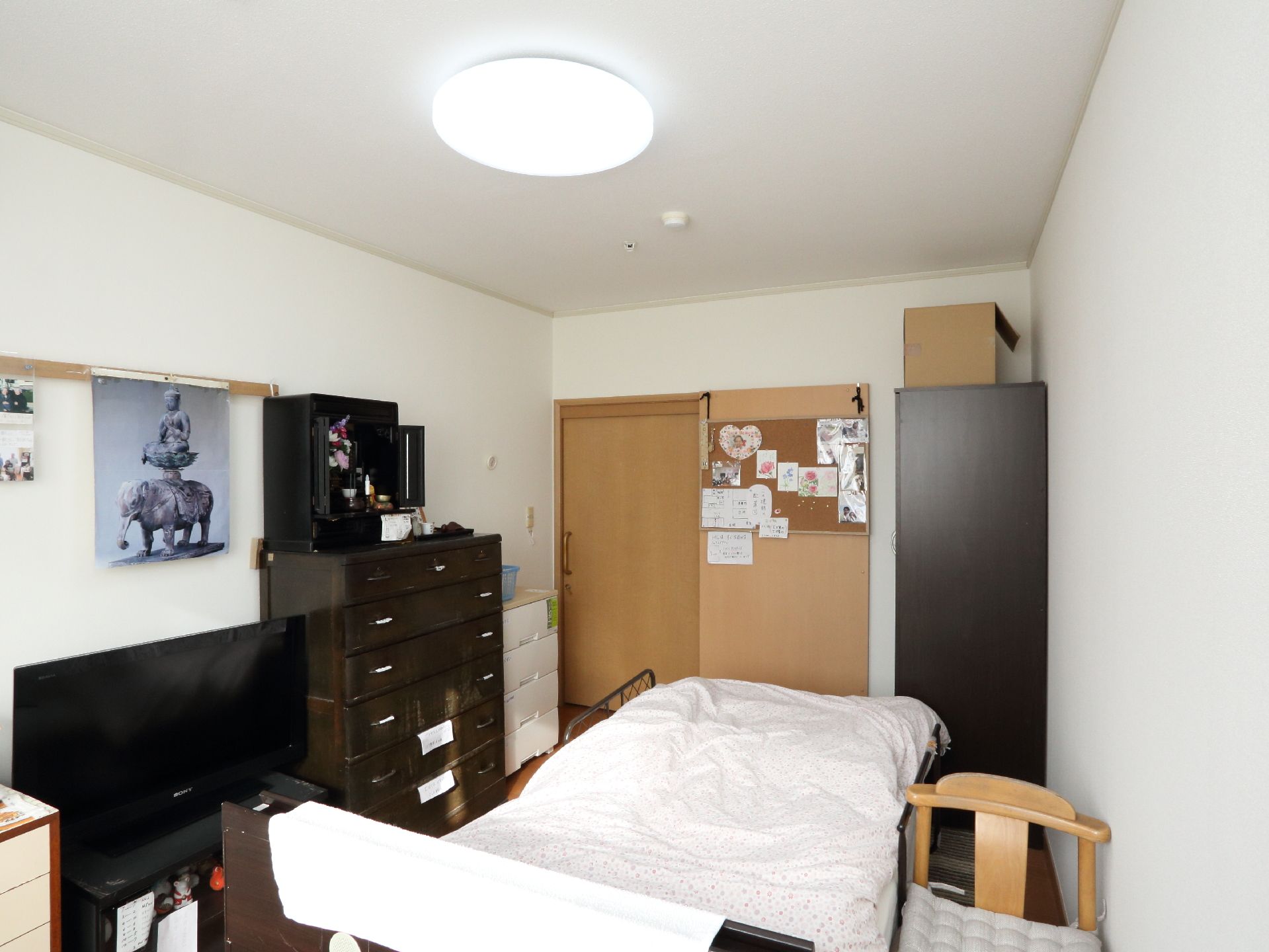 居室内部には、沢山の家具や家電、電動ベッドなどが置かれている。壁にはポスターが貼られたり、写真が飾られたりしている。
