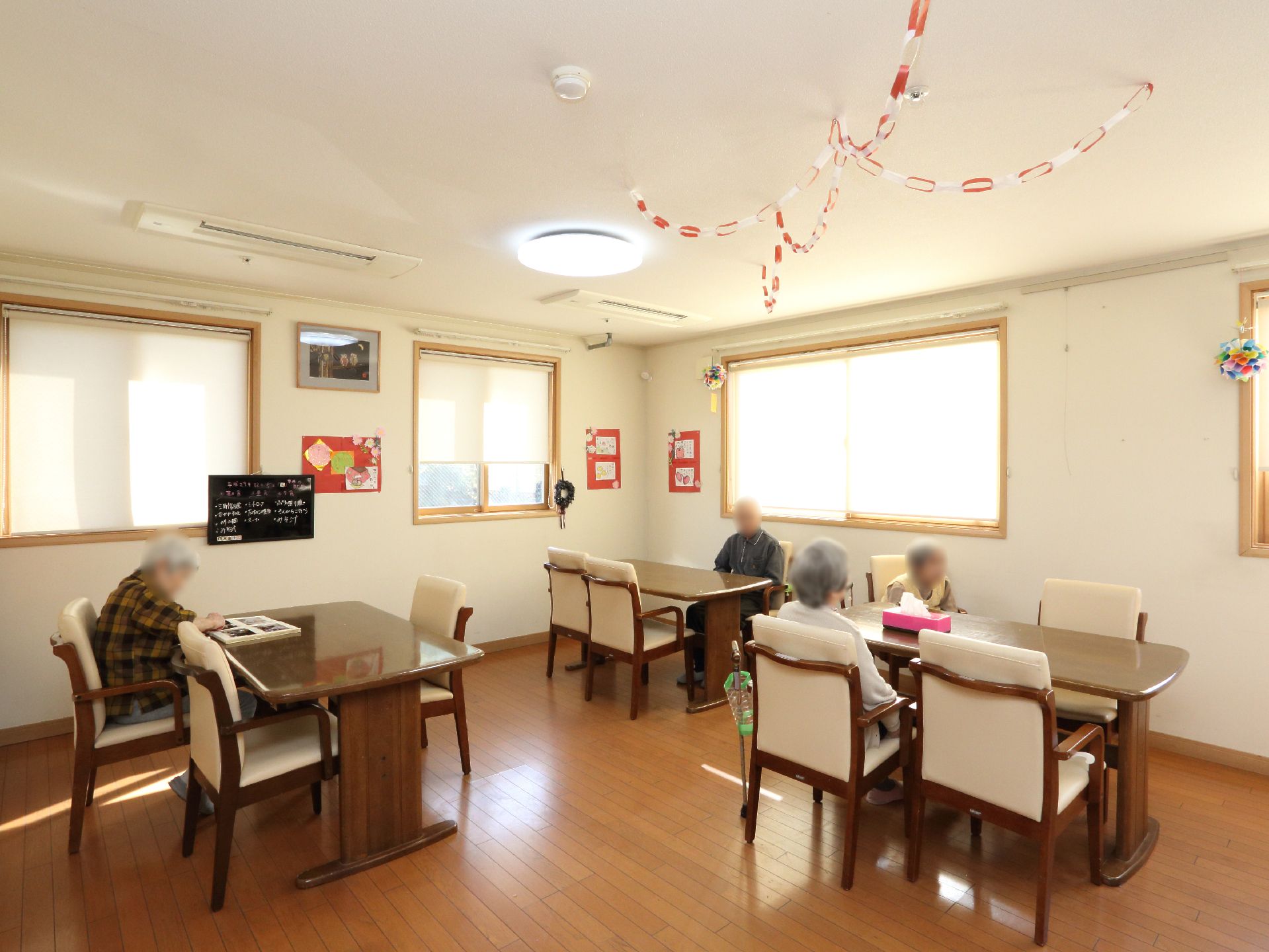 広さのある部屋に、テーブルが数台置かれ、椅子が添えられている。天井や壁には装飾が施されている。床はフローリングで、段差がない。