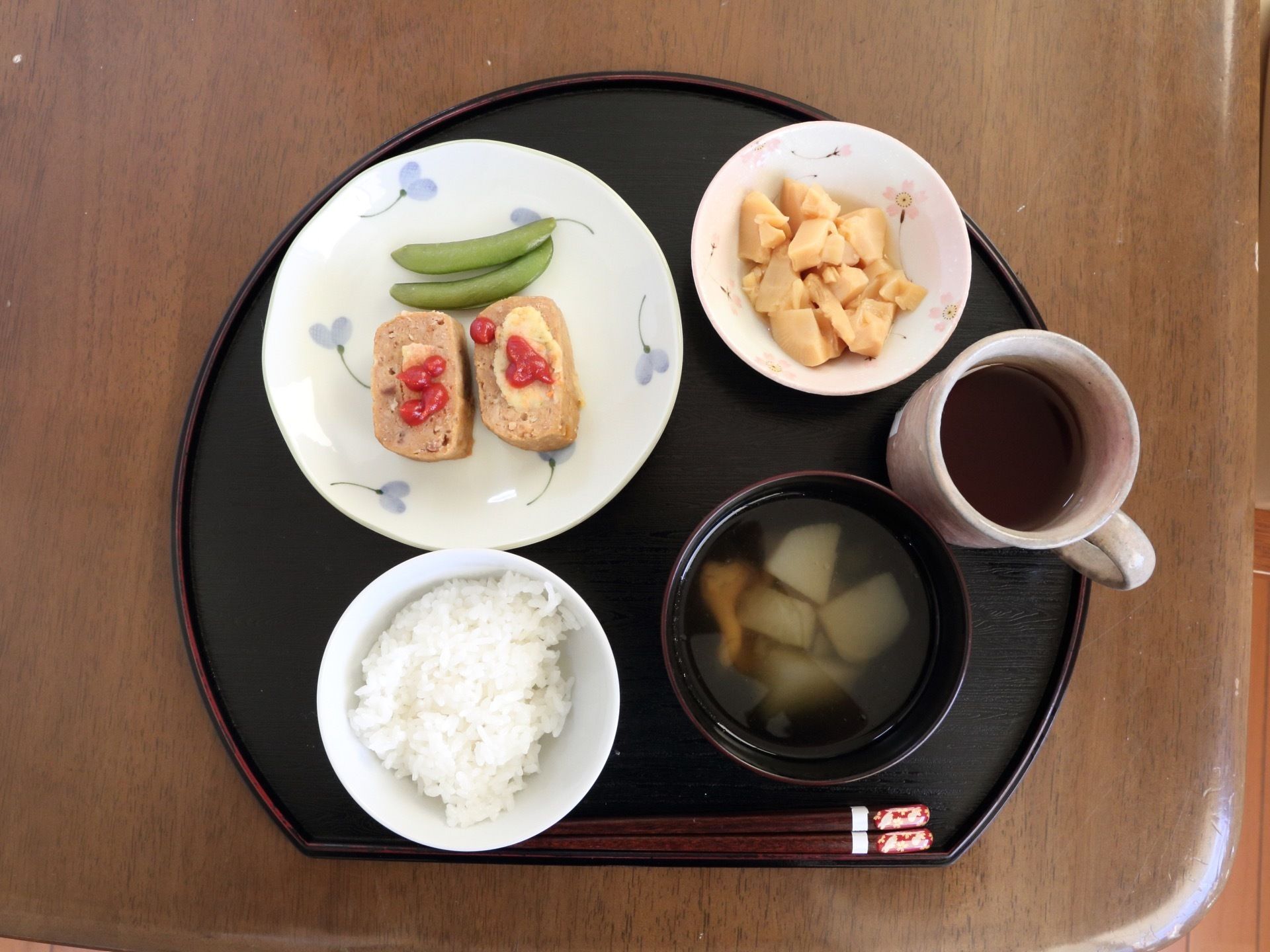 施設で提供される食事の一例。お盆の上にご飯、汁物、おかず、箸休めなどが並べられている。彩の良い食事である。