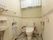 施設内のトイレの様子。洋式の水洗トイレがあり、取り外し可能な手すりが取り付けてある。頭上に収納スペースを設けている。