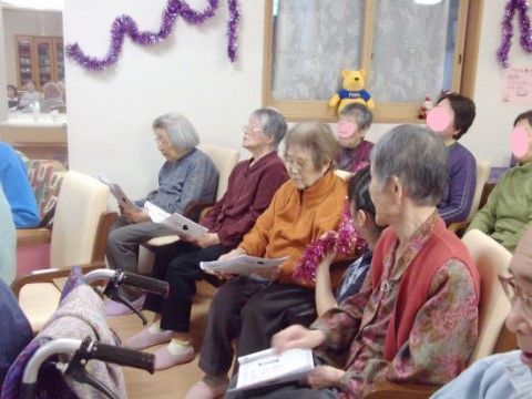 飾り付けがある部屋で、並んで椅子に座り真剣な顔をしている入居者様