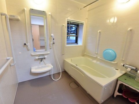 真っ白な壁に手すりが取り付けられた、小窓がついた浴室