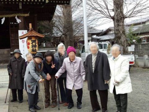 神社の境内の提灯の前で、記念撮影をしている入居者様