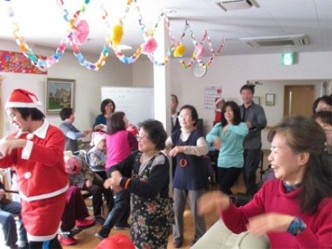 飾り付けされた部屋で、ダンスを踊るサンタの服装をしたスタッフと入居者様たち