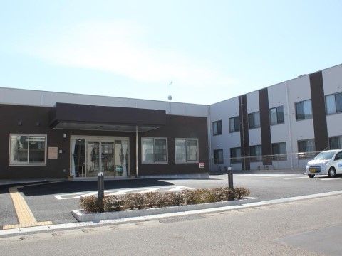 駐車場があり広い敷地に建っている、玄関に庇がついた建物