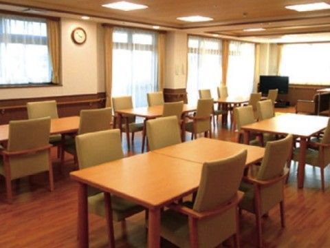 窓がたくさんあり、ダイニングテーブルと椅子が等間隔に並べられた食堂