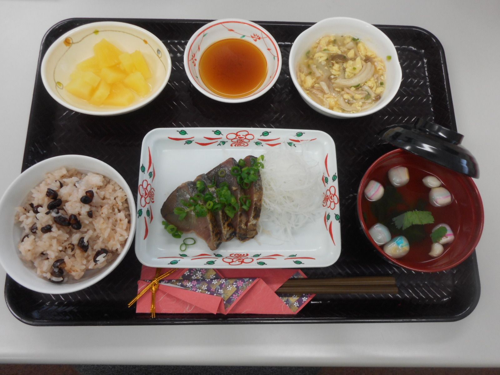 赤飯とカツオのたたきと、吸い物やデザートが付いたメニュー