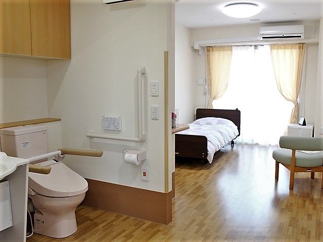 仕切りのないトイレと洗面台が備え付けられた居室。手すりや呼び出しボタンが設置されているため安心して過ごせる。