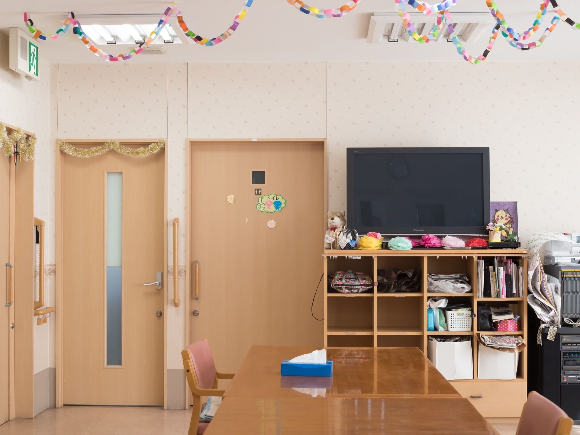 天井には折り紙で作られた作品が飾られている。壁側にテレビがあり、その周囲の棚に本や小物などが置かれている。