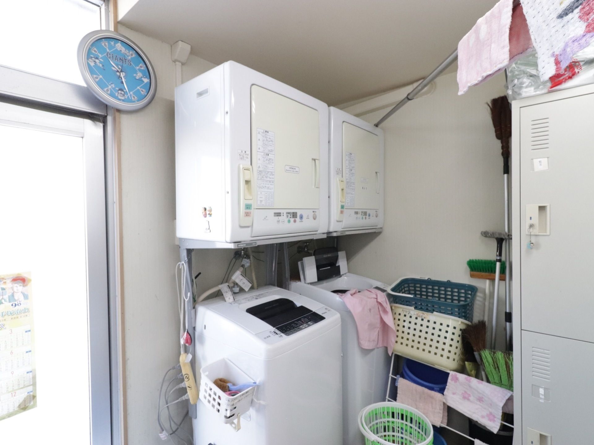 全自動洗濯機に洗濯乾燥機が設置されたものが２セットある。ロッカーや掃除用具も配備されており時計が掛けられている。
