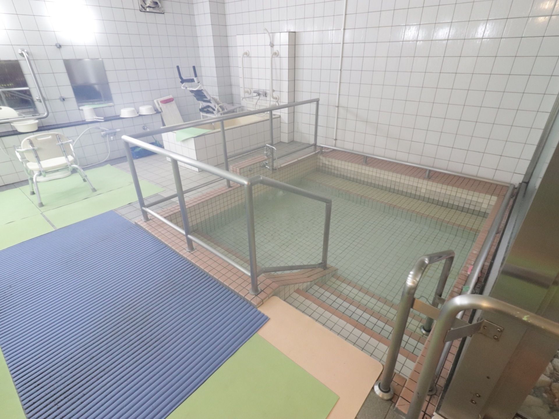 広い温泉のような浴室は足を伸ばして入浴できる。浴槽は階段を下がって入るタイプで、手すりを使ってゆっくり出入りでき安全。