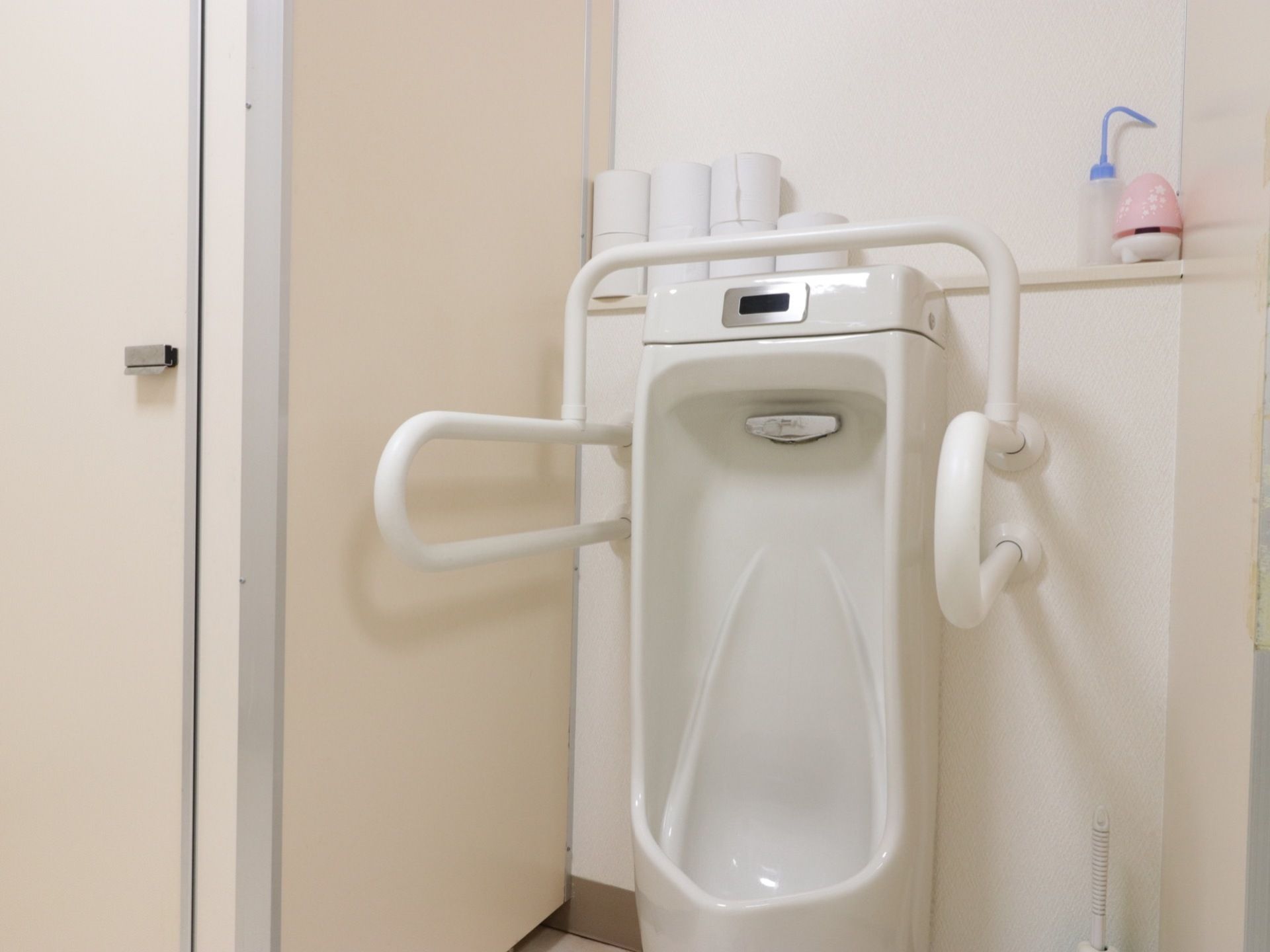 男性用小便器には自動洗浄が付いているので手を触れることなく水を流すことができる。周囲にはしっかりつかまれる手すりが付いている。