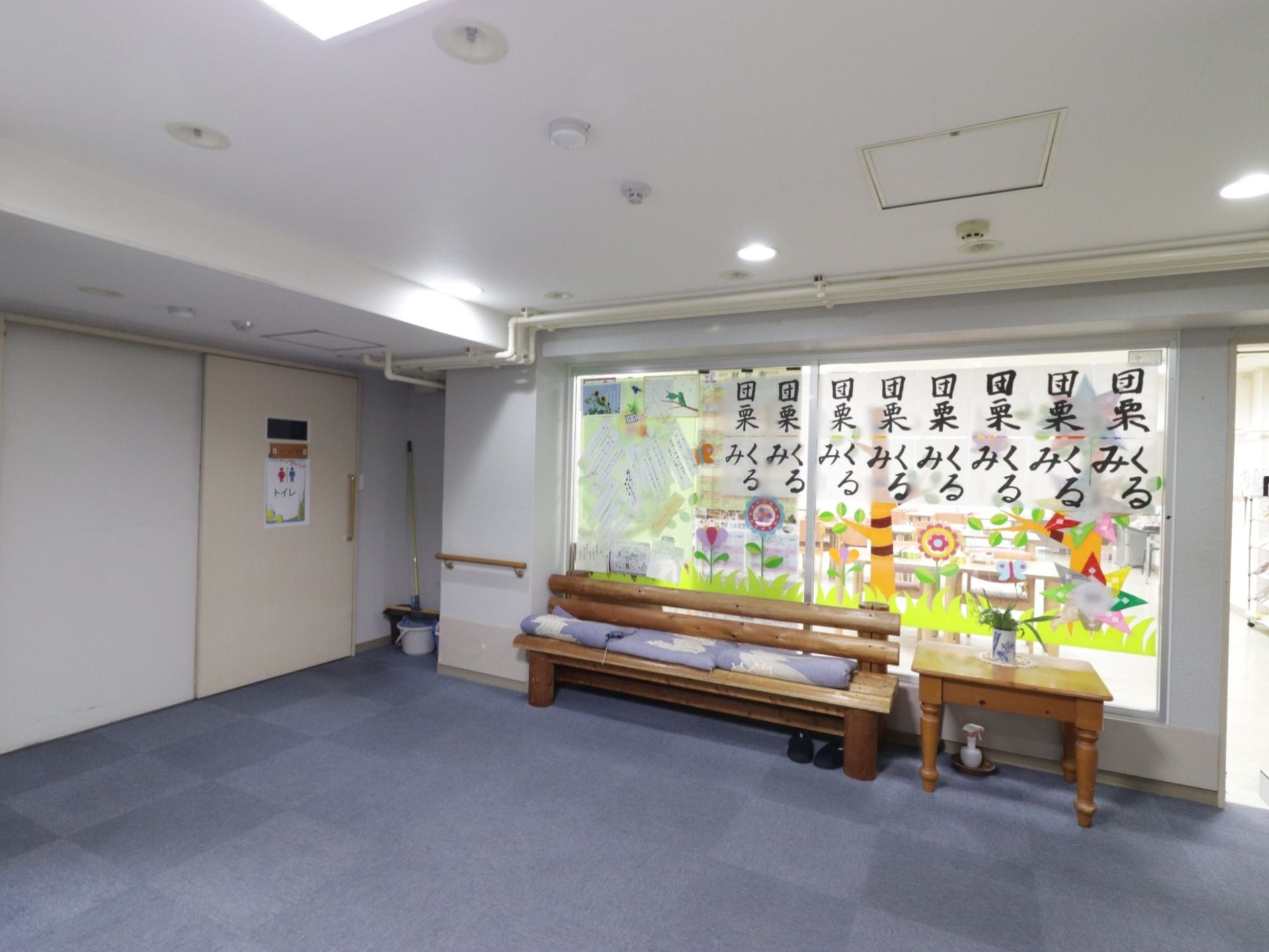 カーペットが敷かれた広々としたエントランスには、施設の活動で作成した入居者様の作品が多数飾られている。