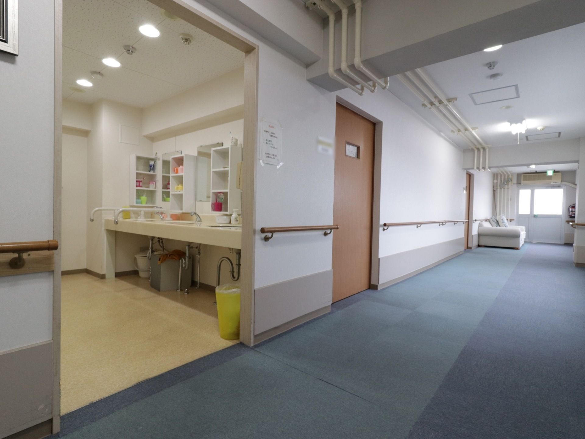 複数の洗面台が設置された洗面所の入口には、出入りしやすいように扉などはない。車椅子のまま使用できるように洗面台の足元を広くとっている。
