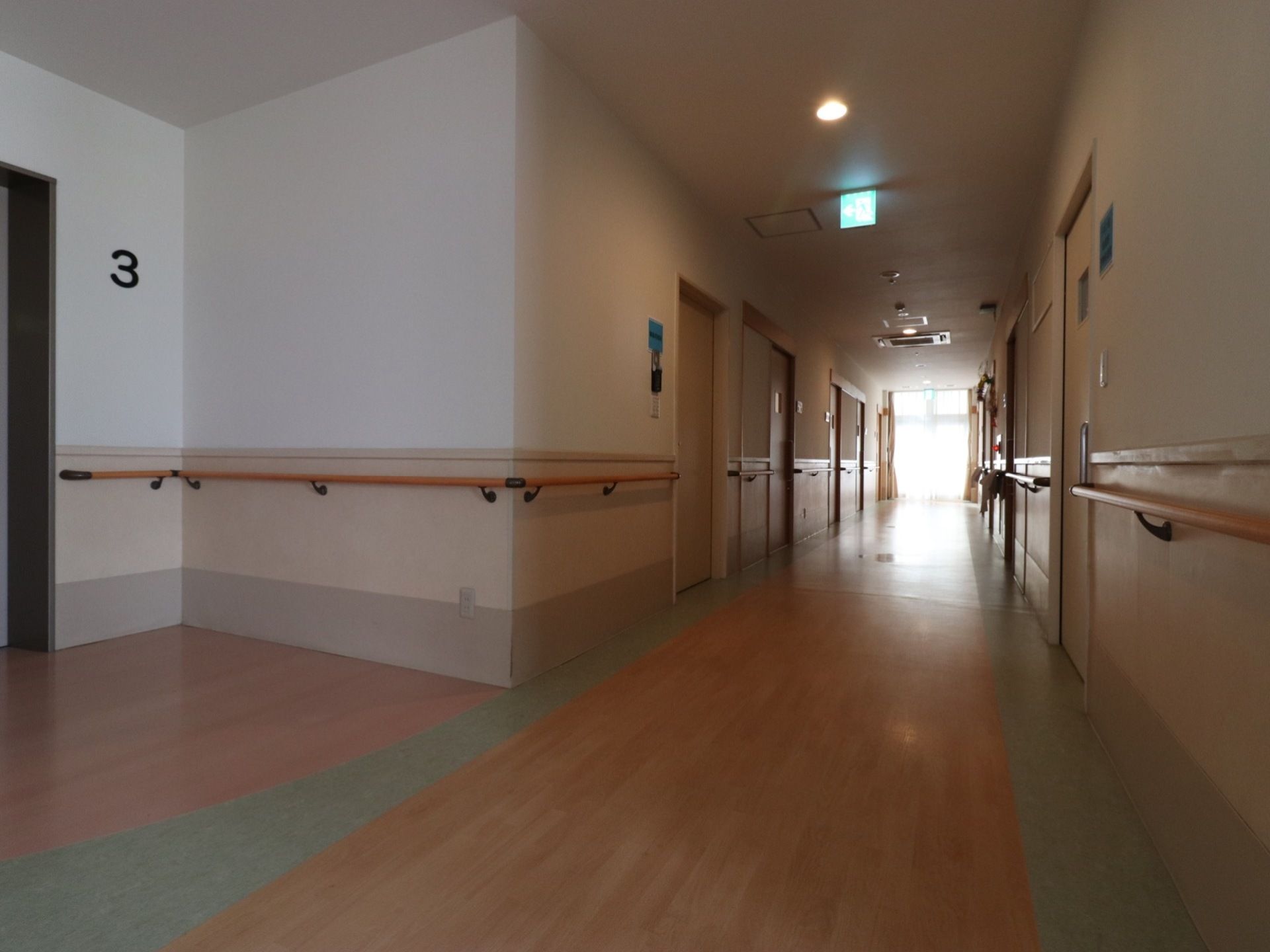 廊下は障害がなく真っ直ぐで通行しやすい。居室扉以外の壁に手すりがあり、ゆっくり歩行で移動することができる。