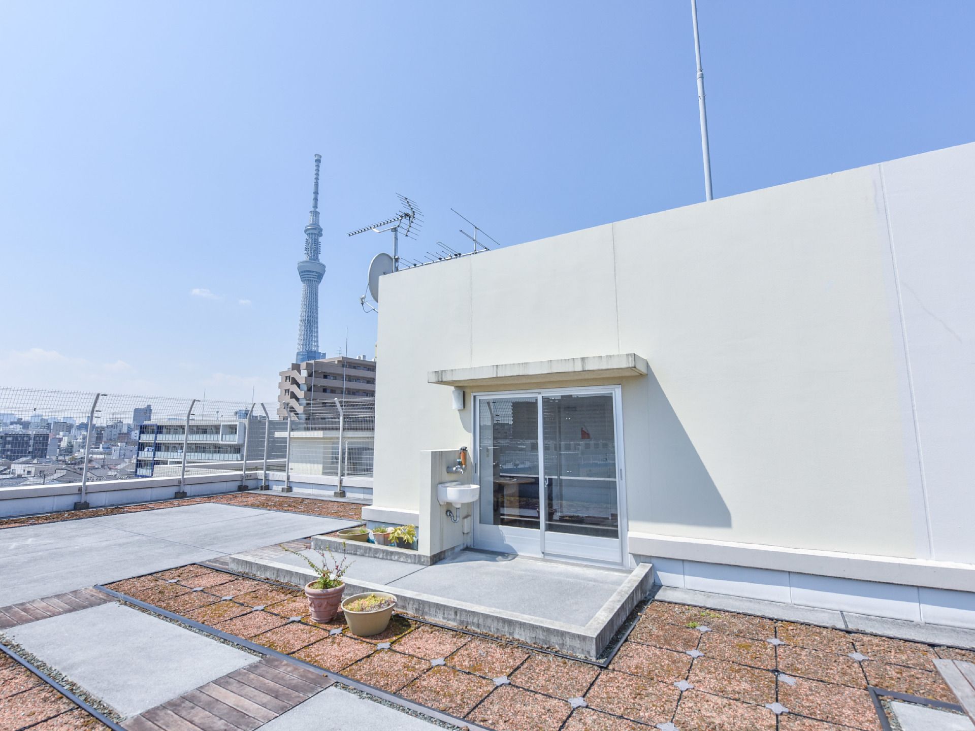 屋上の出入り口はガラス戸で広く作られており車椅子での出入りも可能。手洗い場も設置されている。遠くにはスカイツリーが見える。