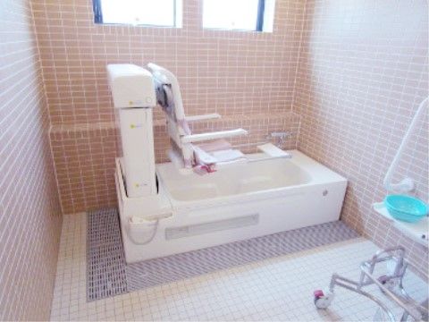 入浴用リフトが置かれている、タイル貼りで窓がある浴室