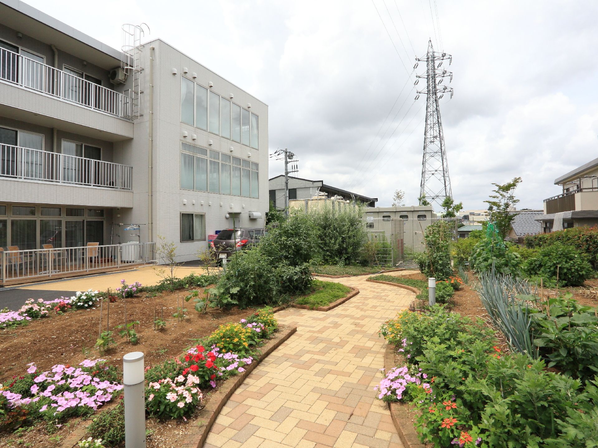 閑静な住宅街に立地している施設の敷地は広々としたガーデンが造られており、花や木の他、野菜も植えられている。