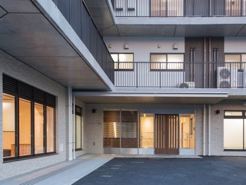 玄関扉は格子状の自動扉でモダンな雰囲気がある。窓が多く中の様子も分かりやすい。玄関前には広いスペースがある。