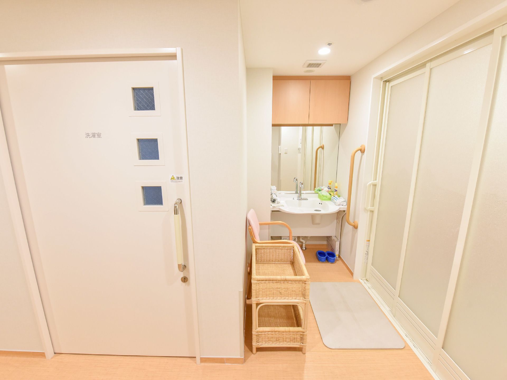 脱衣所の奥には洗面台と鏡があり着替えに利用できる。椅子もあり休憩も可能。手前の通路には洗濯室へのドアが見える。