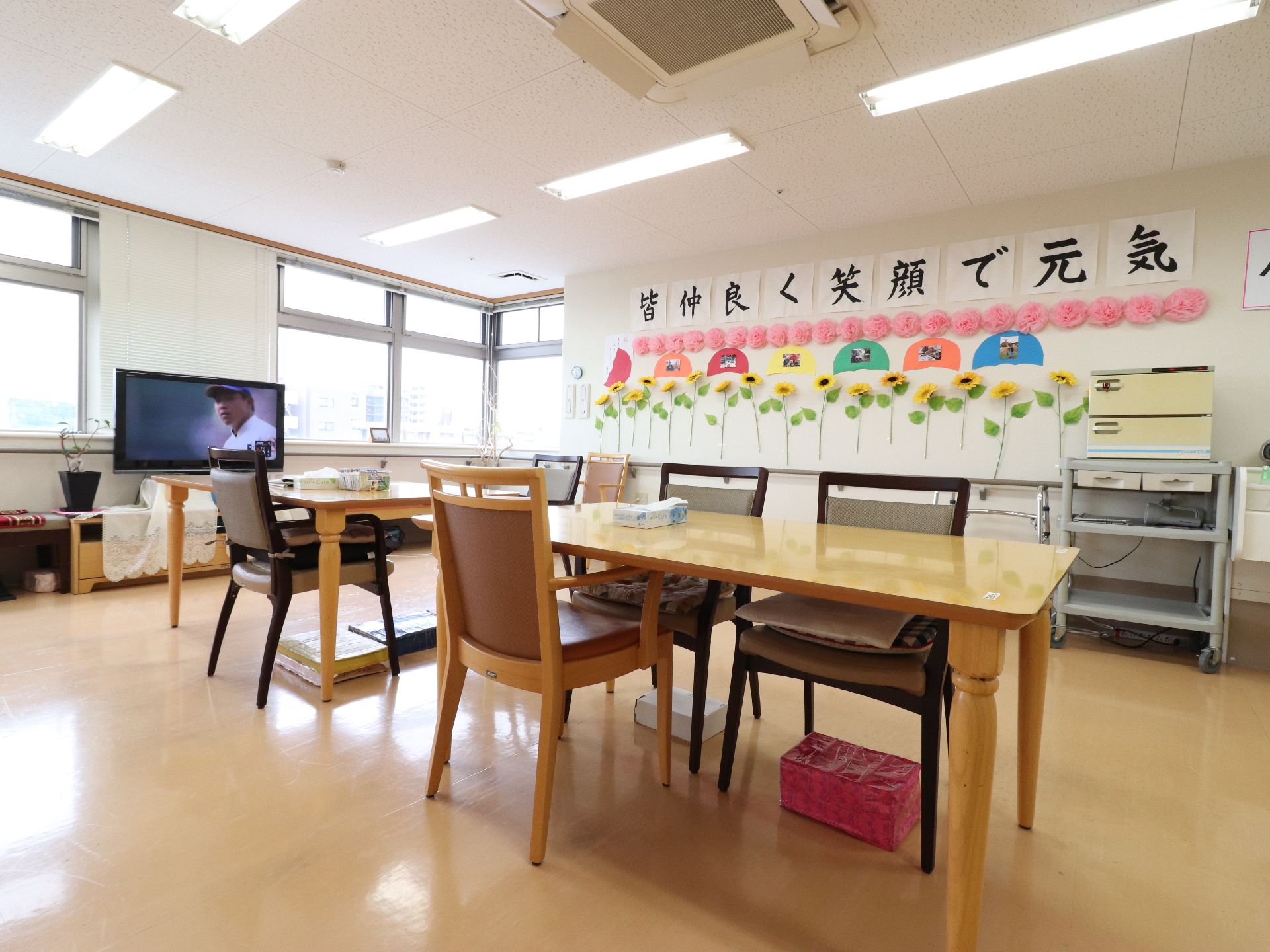 食堂に木目調のテーブル2台が置かれている。その上にはティッシュペーパーが設置されており足元にはクズ篭がある。
