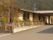 平屋建てのグループホームである。建物の周りに建てられた白いフェンスには、施設名が書かれた看板が取り付けられている。