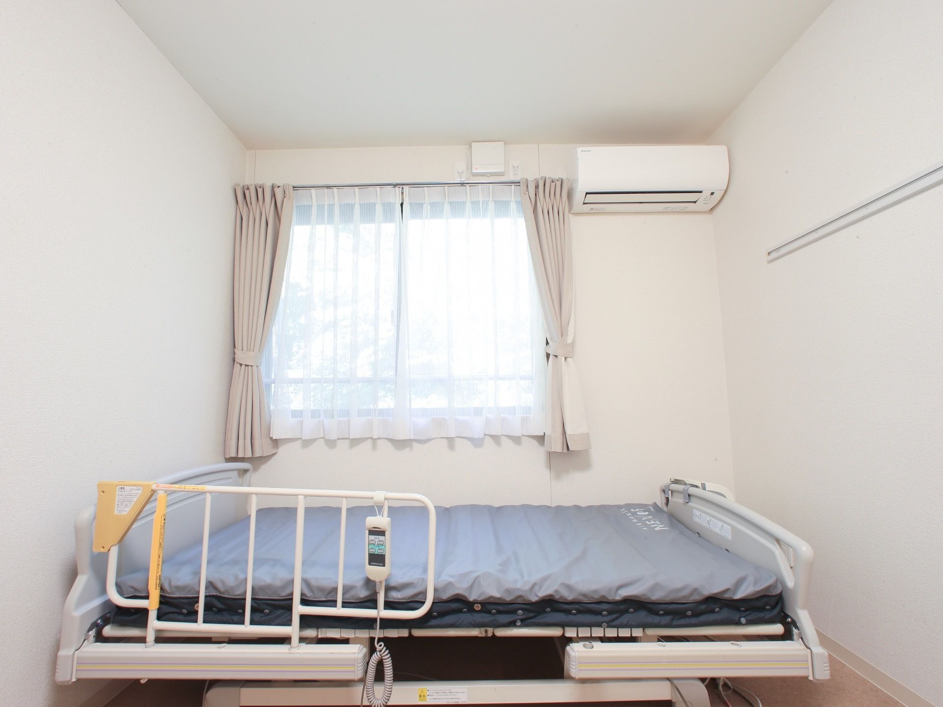 居室には、介護用ベッドが設置されており、起き上がりの動作の補助に利用できる。また、転落防止用のための柵が設置されている。