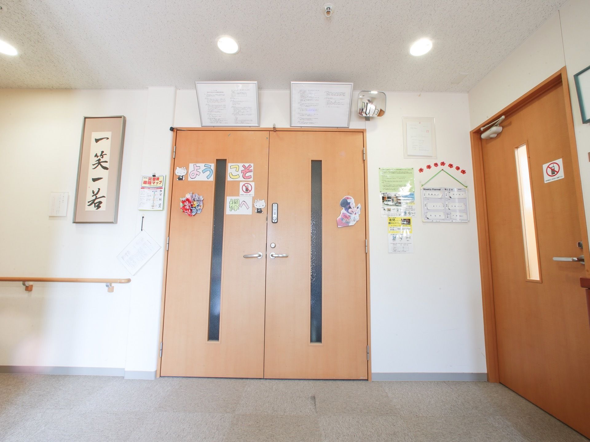 部屋の入口ドアには、かわいいキャラクターの絵が飾られている。タクシー会社の電話番号や、担当スタッフの名前が書かれた紙などが掲示してある。