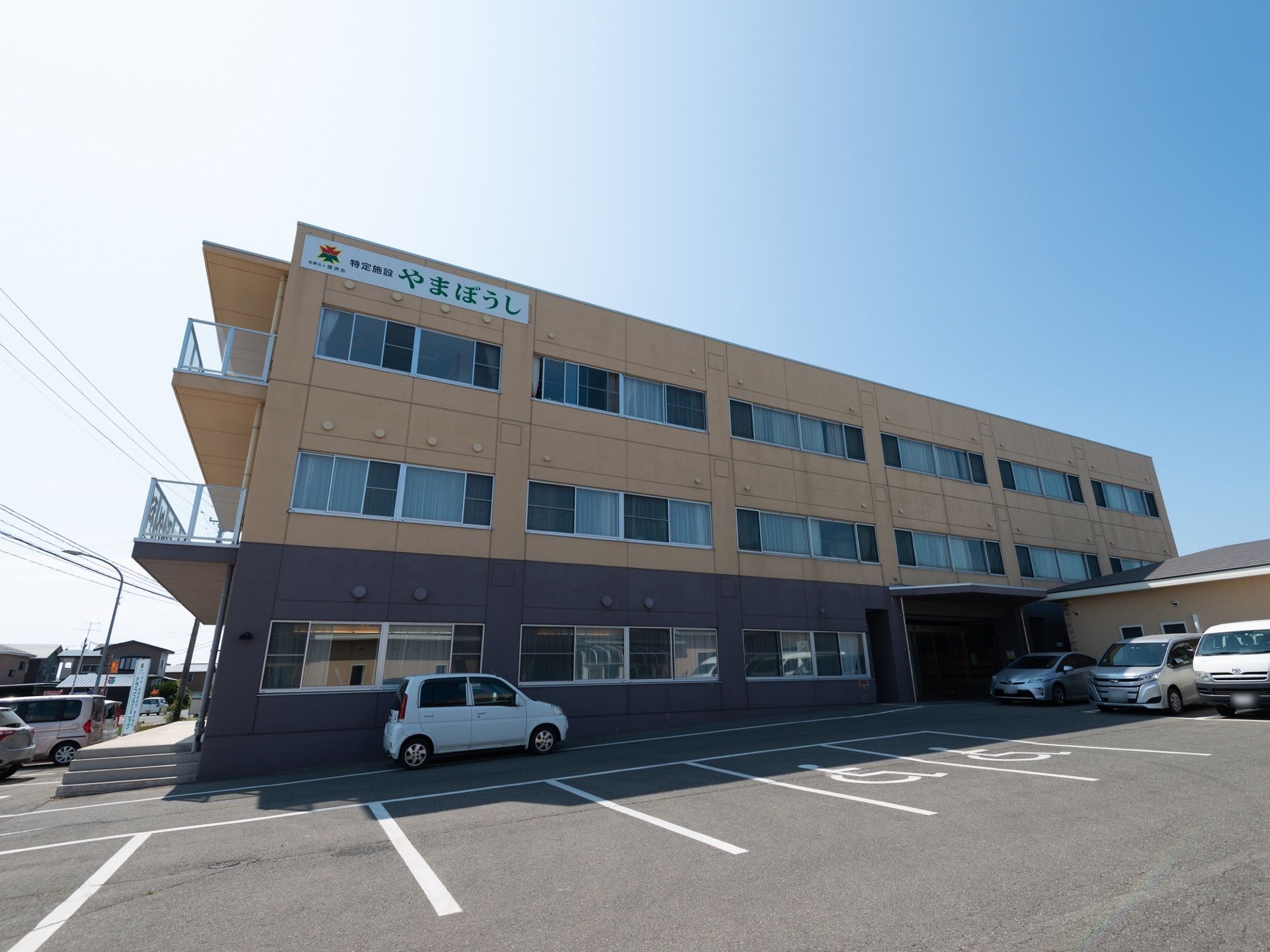 ３階建ての建物で、３階部分には大きな文字で施設名が書いてある。建物の側面には、ベランダが設置されている。