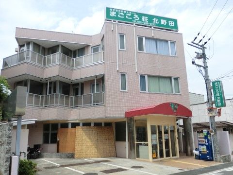 まごころ荘 北野田の外観。赤いエントランスルーフが印象的な施設外観。来訪者専用の駐車場を完備しております。