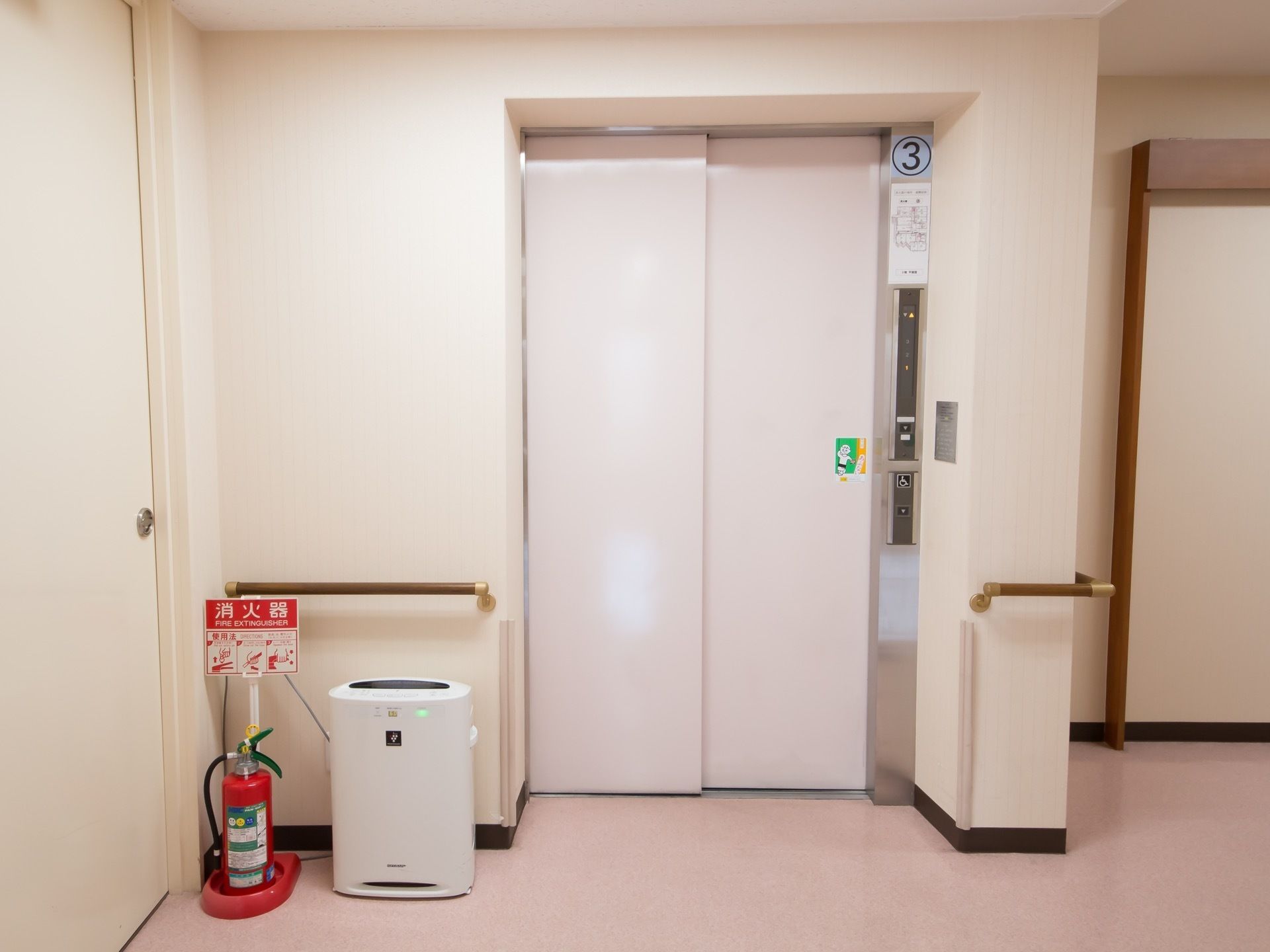 施設の中にはエレベーターが設置されている。エレベーターの前の壁には手すりがあり、つかまって待つことができる。
