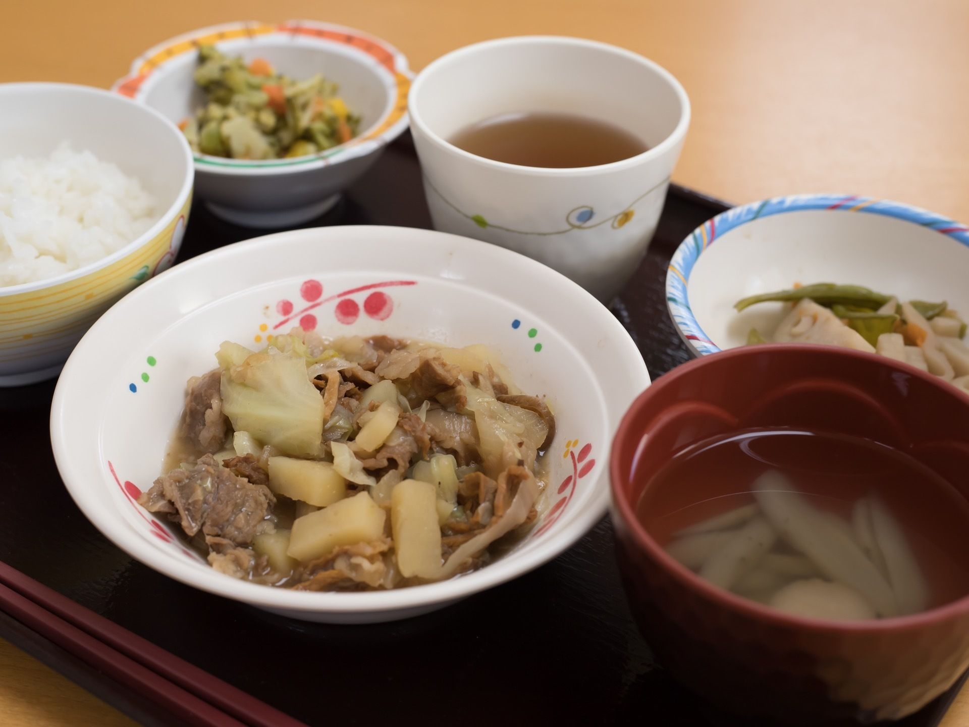 食事は四角い黒のお盆の上にのせられている。この日のメニューはご飯、お吸い物、牛肉とジャガイモの煮物など、栄養バランスのよいメニューである。