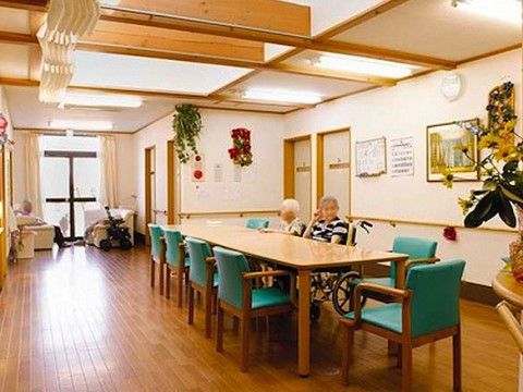 フローリングの床のリビングの中央に、テーブルと椅子が並べられている。入居者様がテーブルを囲み、食事や歓談を楽しんでいる。